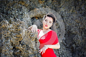 Young beautiful Asian girl in red dress on the beach of a tropic