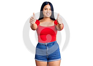 Young beautiful asian girl wearing casual clothes approving doing positive gesture with hand, thumbs up smiling and happy for