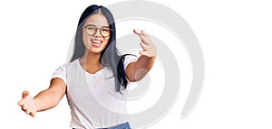 Young beautiful asian girl wearing casual clothes and glasses looking at the camera smiling with open arms for hug