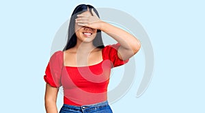 Young beautiful asian girl wearing casual clothes smiling and laughing with hand on face covering eyes for surprise