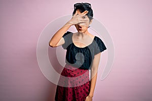 Young beautiful asian girl wearing casual dress standing over isolated pink background peeking in shock covering face and eyes