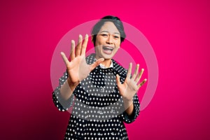 Young beautiful asian girl wearing casual jacket standing over isolated pink background afraid and terrified with fear expression