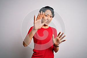 Young beautiful asian girl wearing casual red t-shirt standing over isolated white background afraid and terrified with fear