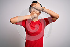 Young beautiful asian girl wearing casual red t-shirt standing over isolated white background Covering eyes and mouth with hands,