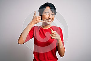 Young beautiful asian girl wearing casual red t-shirt standing over isolated white background smiling doing talking on the