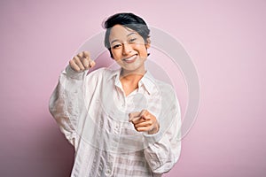 Young beautiful asian girl wearing casual shirt standing over isolated pink background pointing to you and the camera with
