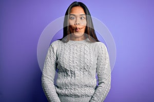 Young beautiful asian girl wearing casual sweater standing over isolated purple background making fish face with lips, crazy and