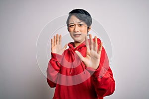 Young beautiful asian girl wearing casual sweatshirt with hoodie over white background afraid and terrified with fear expression