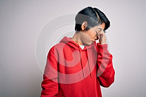 Young beautiful asian girl wearing casual sweatshirt with hoodie over white background tired rubbing nose and eyes feeling fatigue