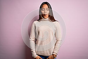 Young beautiful asian girl wearing casual turtleneck sweater over isolated pink background making fish face with lips, crazy and