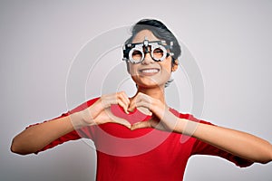 Young beautiful asian girl wearing optometry glasses standing over isolated white background smiling in love showing heart symbol