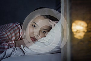 Young beautiful Asian Korean girl lying on bed late night awake looking thoughtful suffering insomnia sleeping disorder feeling