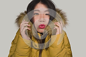 Young beautiful Asian Korean woman feeling cold and chilly freezing feeling cold in Winter weather wearing yellow jacket with fur