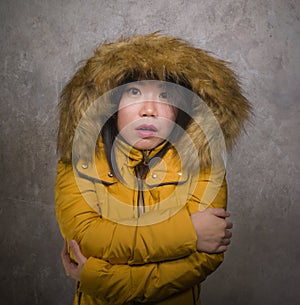 Young beautiful Asian Korean woman feeling cold and chilly freezing feeling cold in Winter weather wearing yellow jacket with fur