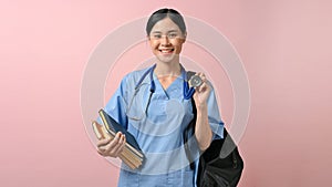 Young beautiful Asian medical student smiling to the camera while holding a bag and books