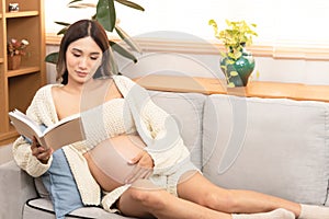 Young beautiful Asian pregnant women reading the book. New mother having a happy time at home