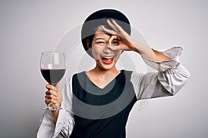 Young beautiful asian sommelier girl drinking glass of red wine over isolated white background with happy face smiling doing ok