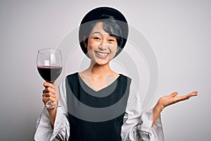 Young beautiful asian sommelier girl drinking glass of red wine over isolated white background very happy and excited, winner