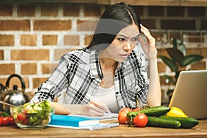 Young beautiful asian stressed woman with laptop on kitchen. Working home. In stress.