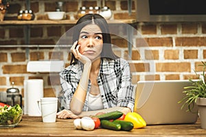 Young beautiful asian stressed woman with laptop on kitchen. Working home. In stress.