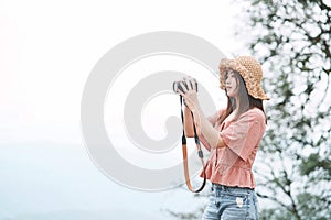Young beautiful Asian traveler woman using digital compact camera and smile, looking at copy space.