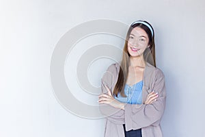 Young beautiful Asian woman in a blue shirt is standing with her arms crossed on a white background