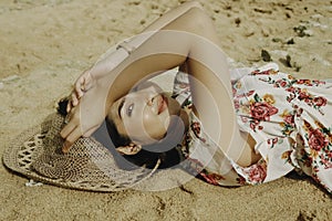 A young beautiful Asian woman dazzled by the light while lying on the beach sand