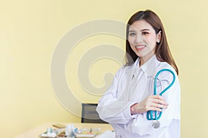 Young beautiful Asian woman doctor Standing with arms crossed happy and smile in hospital. Wearing a white robe and stethoscope