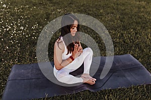 young beautiful asian woman doing yoga in a park at sunset. Yoga and healthy lifestyle concept
