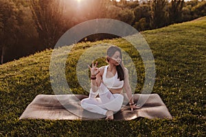 young beautiful asian woman doing yoga in a park at sunset. Yoga and healthy lifestyle concept