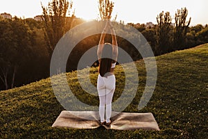 Young beautiful asian woman doing yoga in a park at sunset. Yoga and healthy lifestyle concept