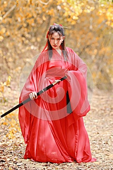 Young beautiful asian woman dress in traditional Chinese old fashion warrior style with ancient word and umbrella. Cute girl in re