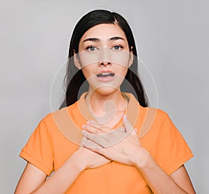 Young beautiful asian woman, long black hair, wore orange t shirt, show Shocked face,Really on gray background