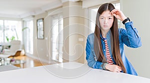 Young beautiful asian woman with long hair wearing denim jacket worried and stressed about a problem with hand on forehead,