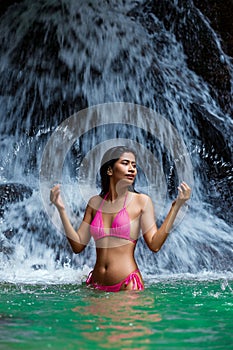 Young beautiful asian woman posing at small waterfall