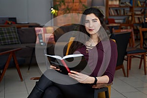 Young beautiful Asian woman reading book in a cafe