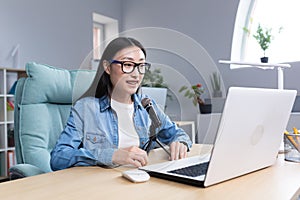 Young beautiful Asian woman recording audio podcast, woman in office using professional microphone