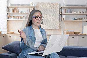 Young beautiful asian woman studying remotely sitting in living room on sofa, female student