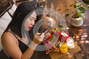 Young beautiful Asian woman takes picture of food with phone for internet blog. Korean girl posting online photo for vegetarian