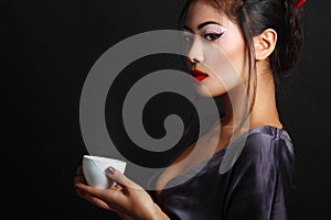 Young beautiful asian woman and tea ceremony, copyspace over black backround