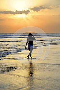 Young beautiful asian woman walking on sand sea shore free and relaxed looking at sun horizon on sunset beach