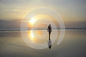 Young beautiful asian woman walking on sand sea shore free and relaxed looking at sun horizon on sunset beach