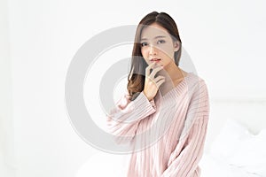 Young beautiful Asian woman in warm knitted pink clothes holding