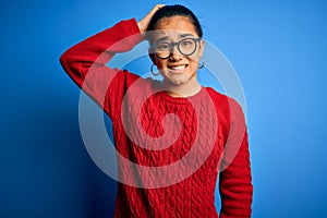 Young beautiful asian woman wearing casual sweater and glasses over blue background confuse and wonder about question