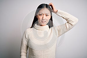 Young beautiful asian woman wearing casual sweater standing over isolated background confuse and wonder about question