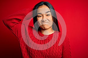 Young beautiful asian woman wearing casual sweater standing over isolated red background confuse and wonder about question