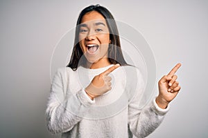 Young beautiful asian woman wearing casual sweater standing over white background smiling and looking at the camera pointing with