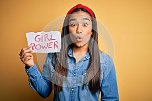 Young beautiful asian woman wearing diadema holding banner with girl power message scared in shock with a surprise face, afraid