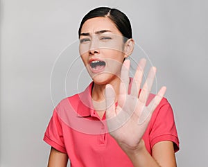 Young beautiful asian woman wore pink t shirt, Raise her hand,Showed prohibit expression , on gray background