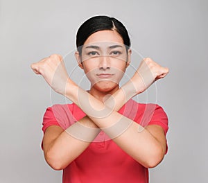 Young beautiful asian woman wore pink t shirt, Showed Crossed hands and serious expression , on gray background